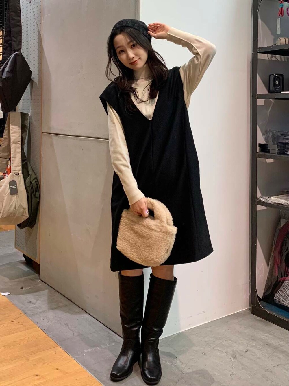 ブラック系のブーツ、ベージュ系のハンドバッグ、ブラック系のワンピースを着用したレディースの冬コーディネートの4枚目の写真