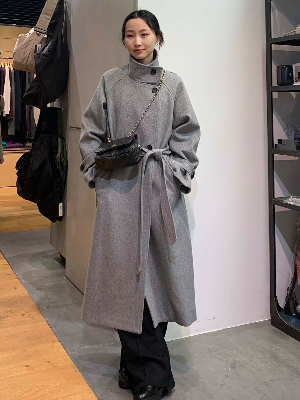 ブラック系のブーツ、ブラック系のショルダーバッグ、グレー系のその他アウターを着用したレディースの冬コーディネートの2枚目の写真