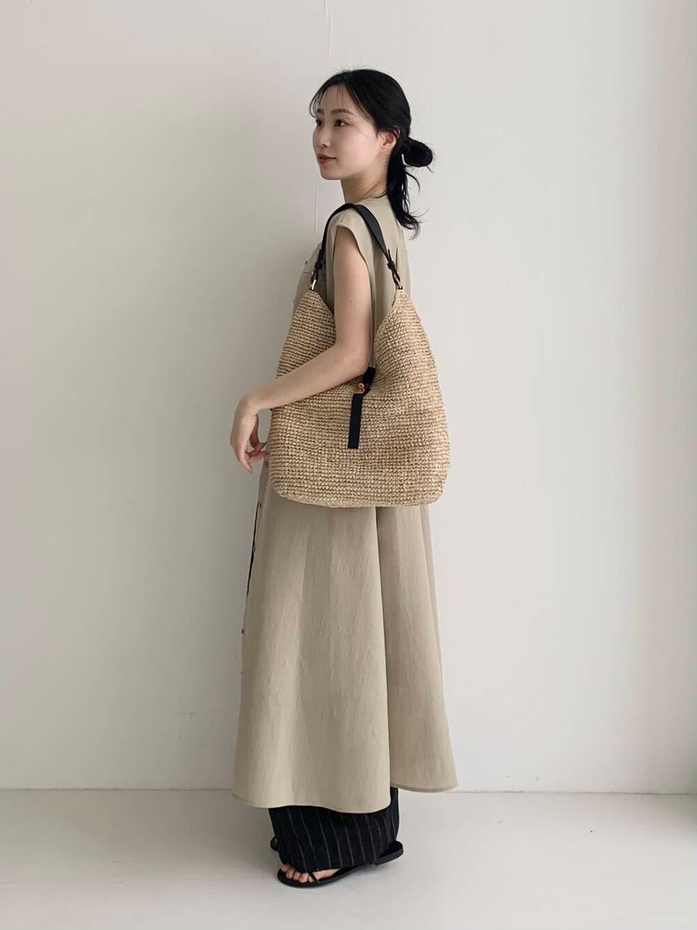 ベージュ系のかごバッグ、ベージュ系のワンピース、ブラック系のその他パンツを着用したレディースの春コーディネートの3枚目の写真