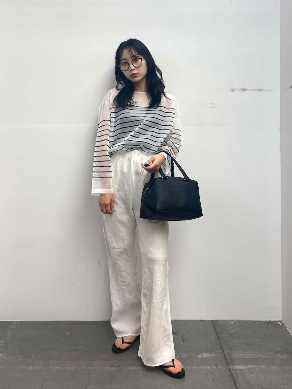 ブラック系のサンダル、ブラック系のハンドバッグ、ホワイト系のその他パンツを着用したレディースの夏コーディネートの2枚目の写真