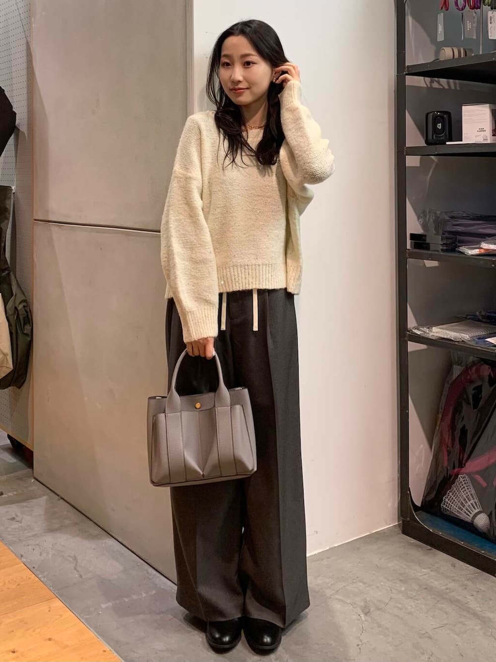 ブラック系のブーツ、グレー系のトートバッグ、ホワイト系のニット/セーターを着用したレディースの冬コーディネートの3枚目の写真
