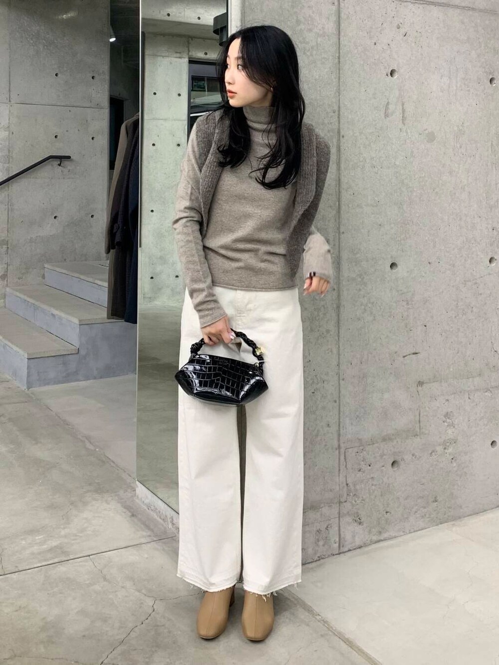 ホワイト系のデニムパンツ、ベージュ系のブーツ、ブラック系のショルダーバッグを着用したレディースの冬コーディネートの4枚目の写真