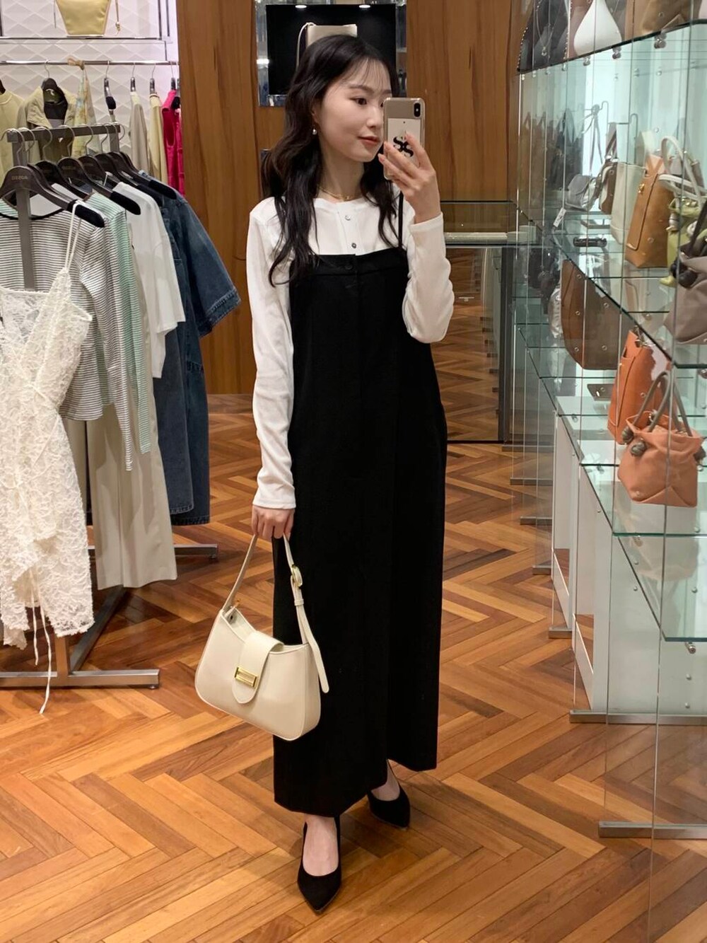 ブラック系のパンプス、ホワイト系のハンドバッグ、ホワイト系のカーディガン/ボレロを着用したレディースの冬コーディネートの2枚目の写真