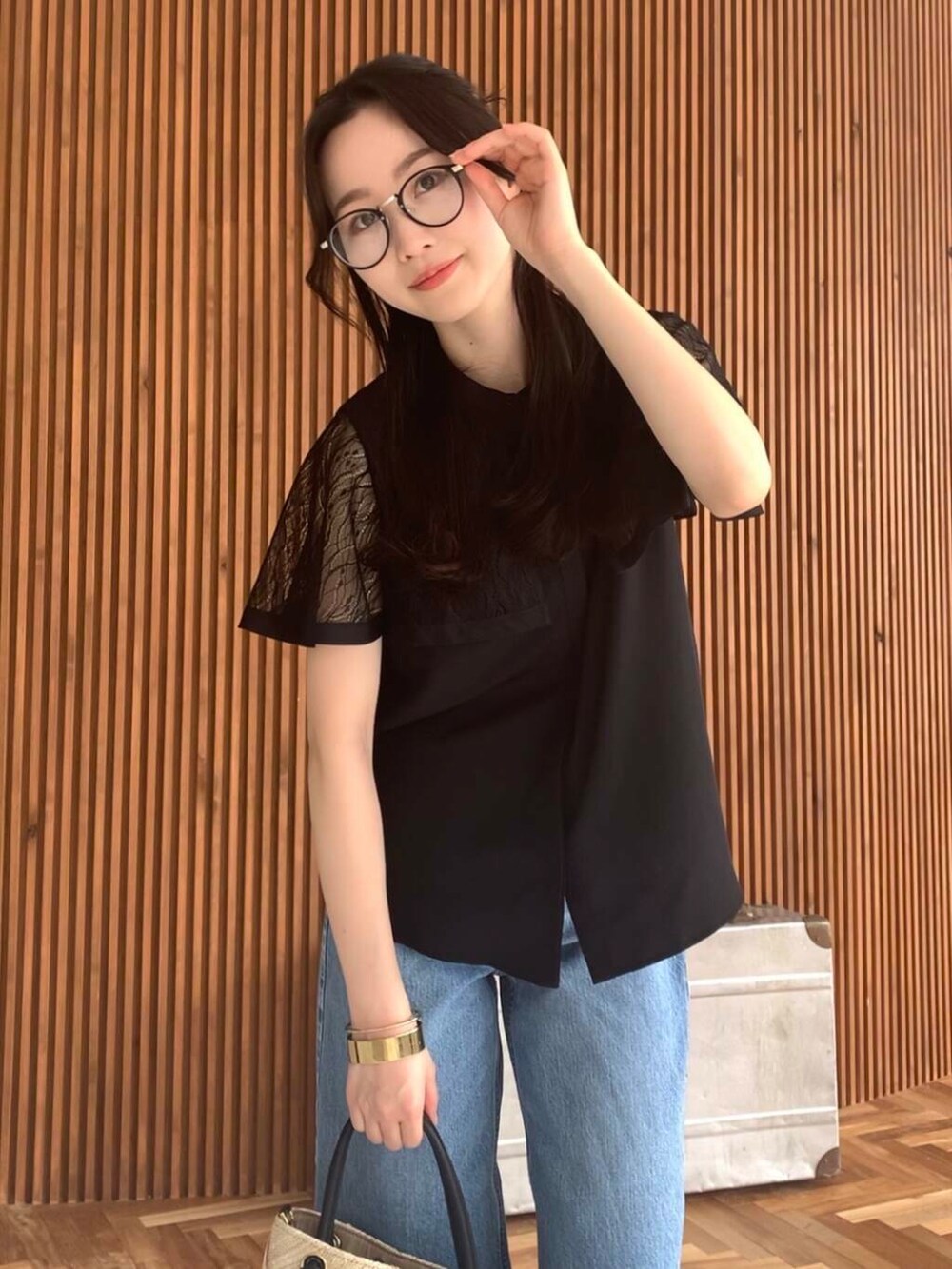 ベージュ系のショルダーバッグ、ブルー系のデニムパンツ、ブラック系のシャツ/ブラウスを着用したレディースの夏コーディネートの3枚目の写真