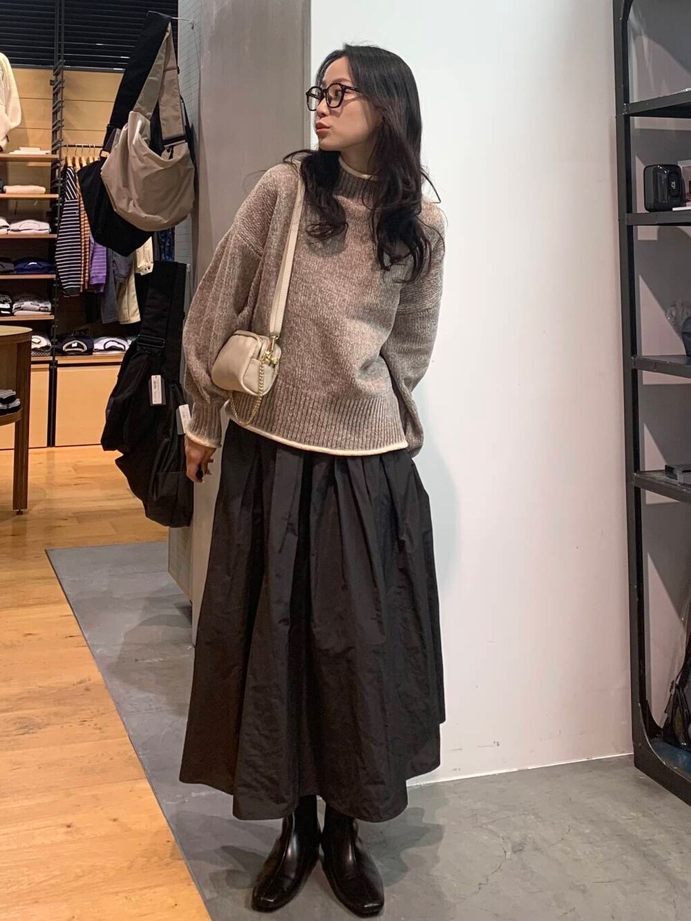 グレー系のスカート、ベージュ系のニット/セーター、ブラック系のブーツを着用したレディースの冬コーディネートの4枚目の写真