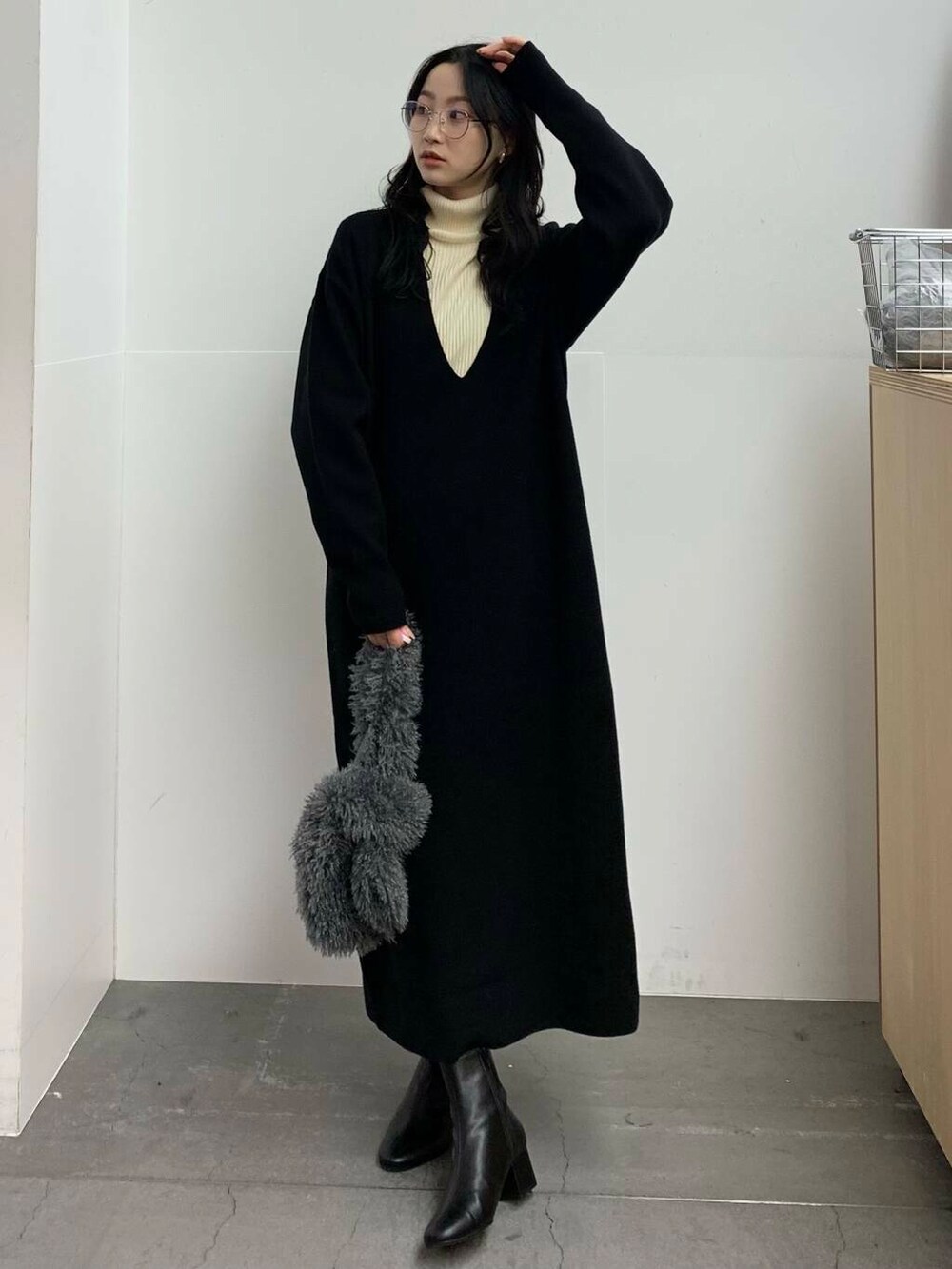 ブラック系のブーツ、グレー系のハンドバッグ、ホワイト系のニット/セーターを着用したレディースの冬コーディネートの2枚目の写真