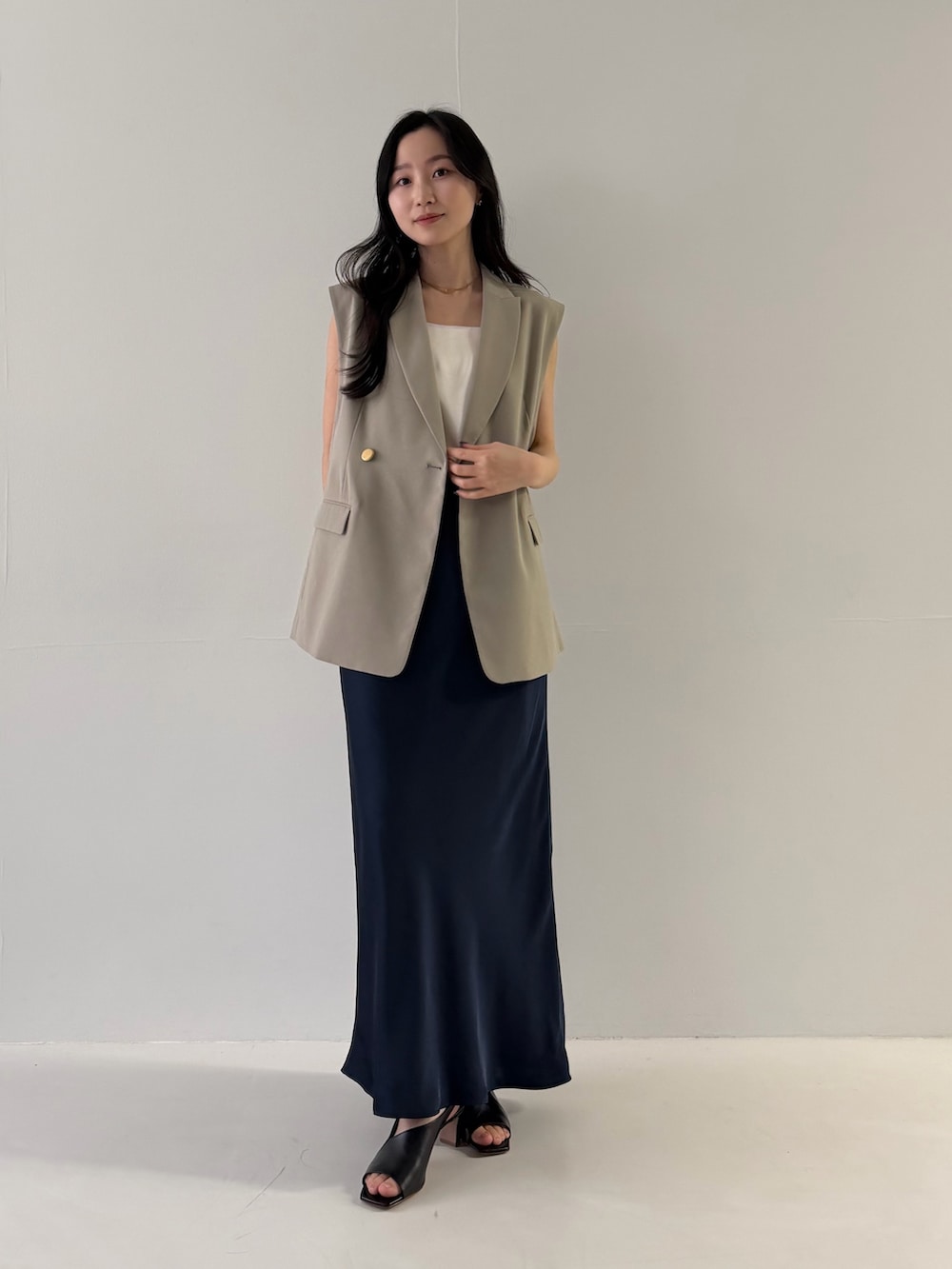 ベージュ系のベスト、ブルー系のスカートを着用したレディースの冬コーディネートの2枚目の写真