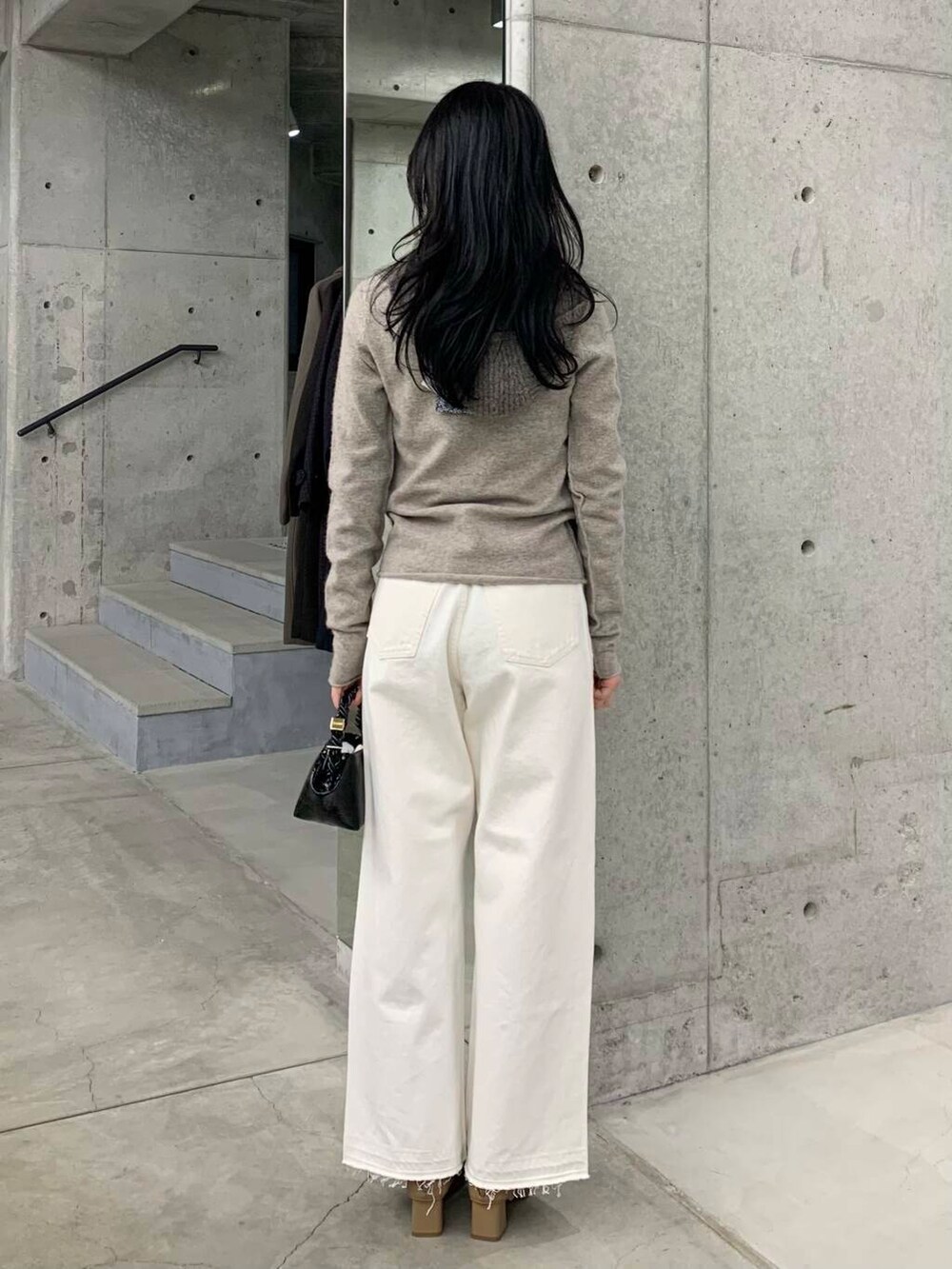 ホワイト系のデニムパンツ、ベージュ系のブーツ、ブラック系のショルダーバッグを着用したレディースの冬コーディネートの6枚目の写真