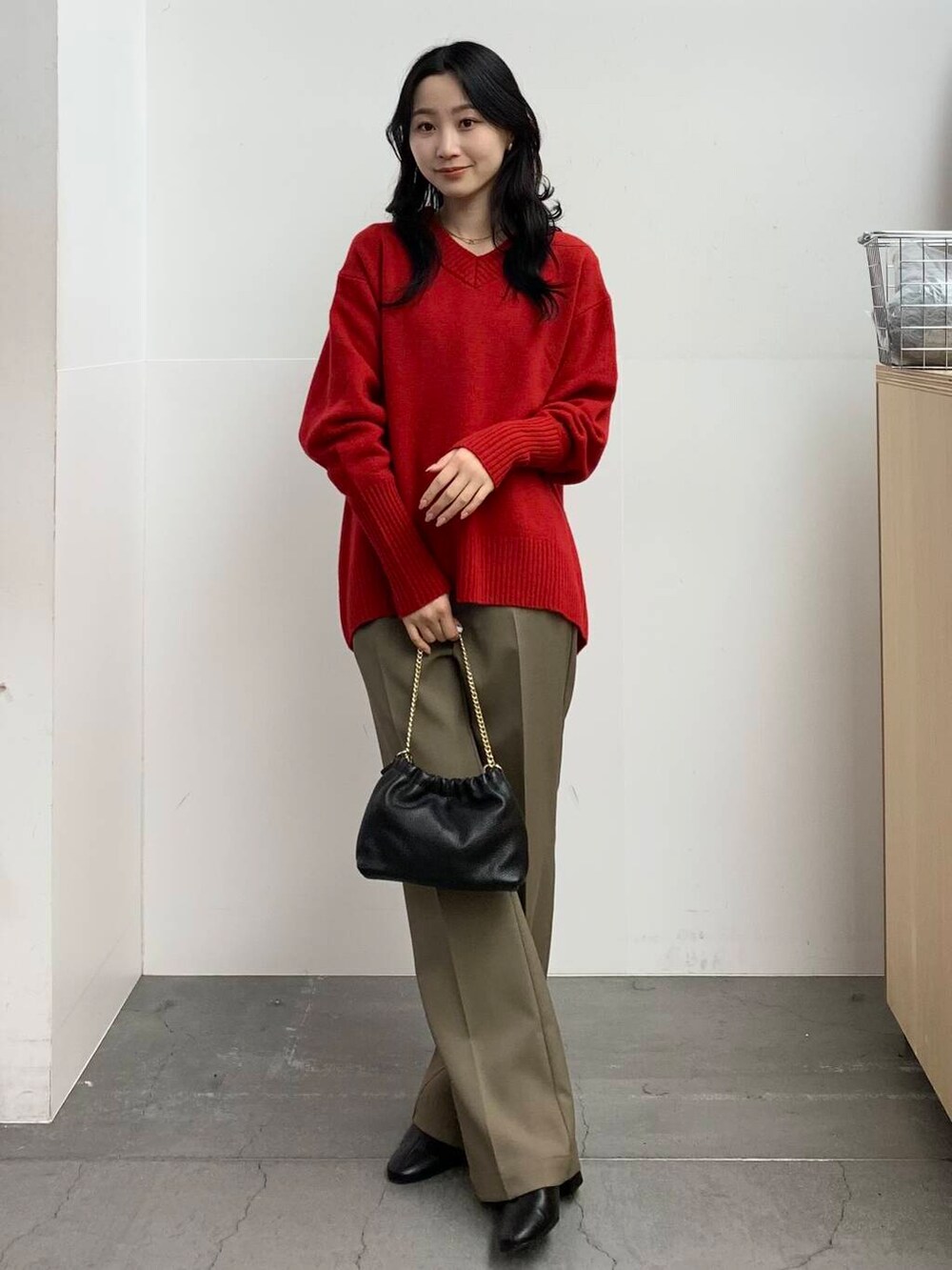 ブラック系のブーツ、レッド系のニット/セーター、ベージュ系のその他パンツを着用したレディースの冬コーディネートの6枚目の写真