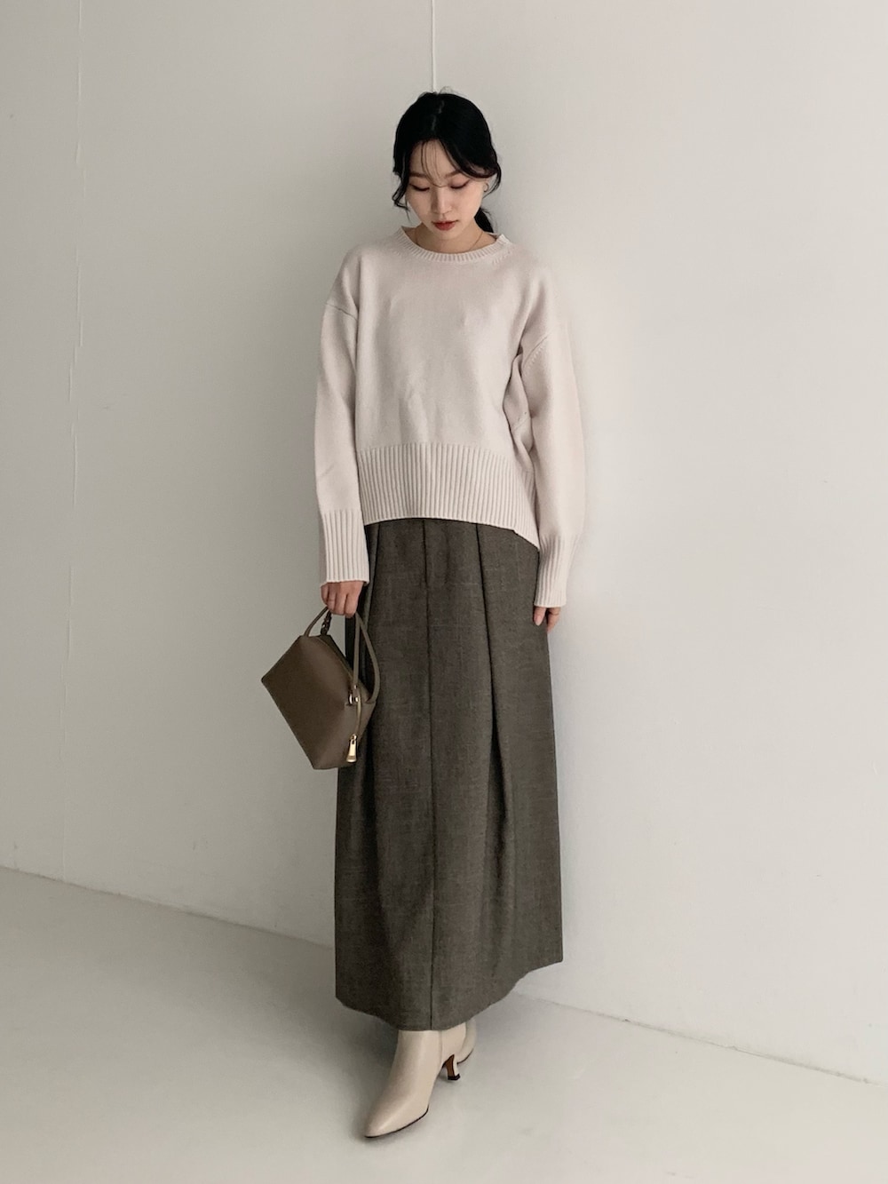 ホワイト系のニット/セーター、ブラウン系のスカート、ブラウン系のハンドバッグを着用したレディースの秋コーディネートの2枚目の写真