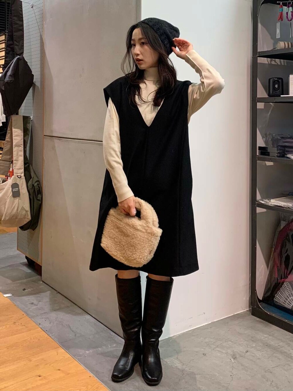 ブラック系のブーツ、ベージュ系のハンドバッグ、ブラック系のワンピースを着用したレディースの冬コーディネートの3枚目の写真