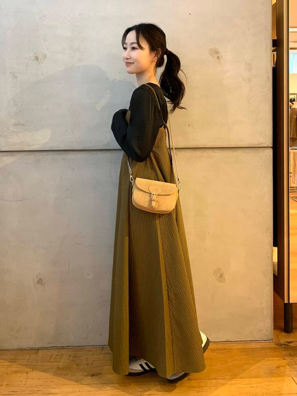 ベージュ系のショルダーバッグ、ホワイト系のスニーカー、ブラウン系のワンピースを着用したレディースの夏コーディネートの4枚目の写真