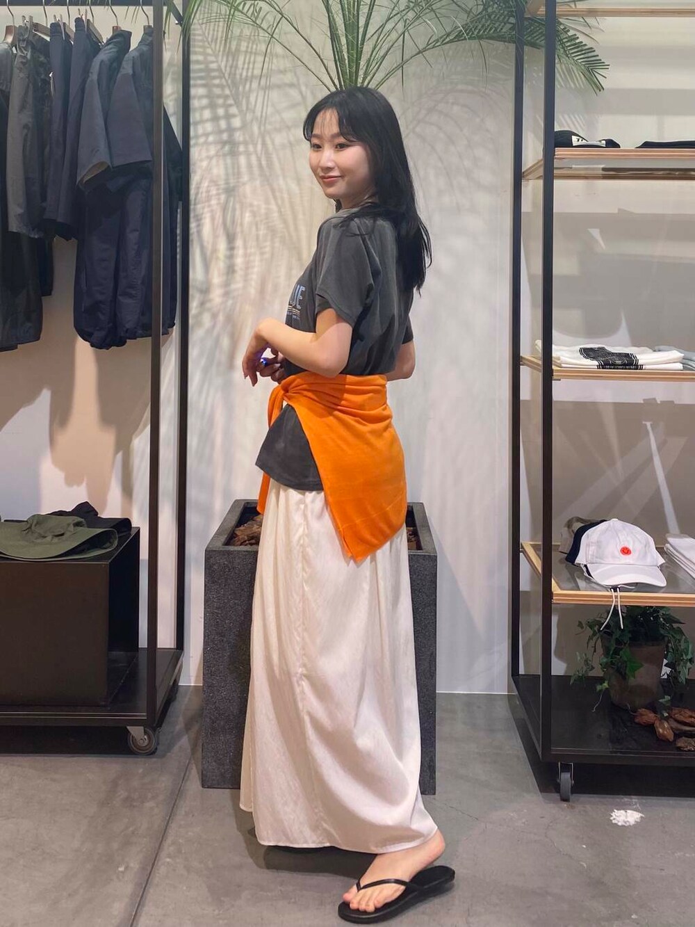 ブラック系のサンダル、オレンジ系のカーディガン/ボレロ、ホワイト系のスカートを着用したレディースの夏コーディネートの4枚目の写真