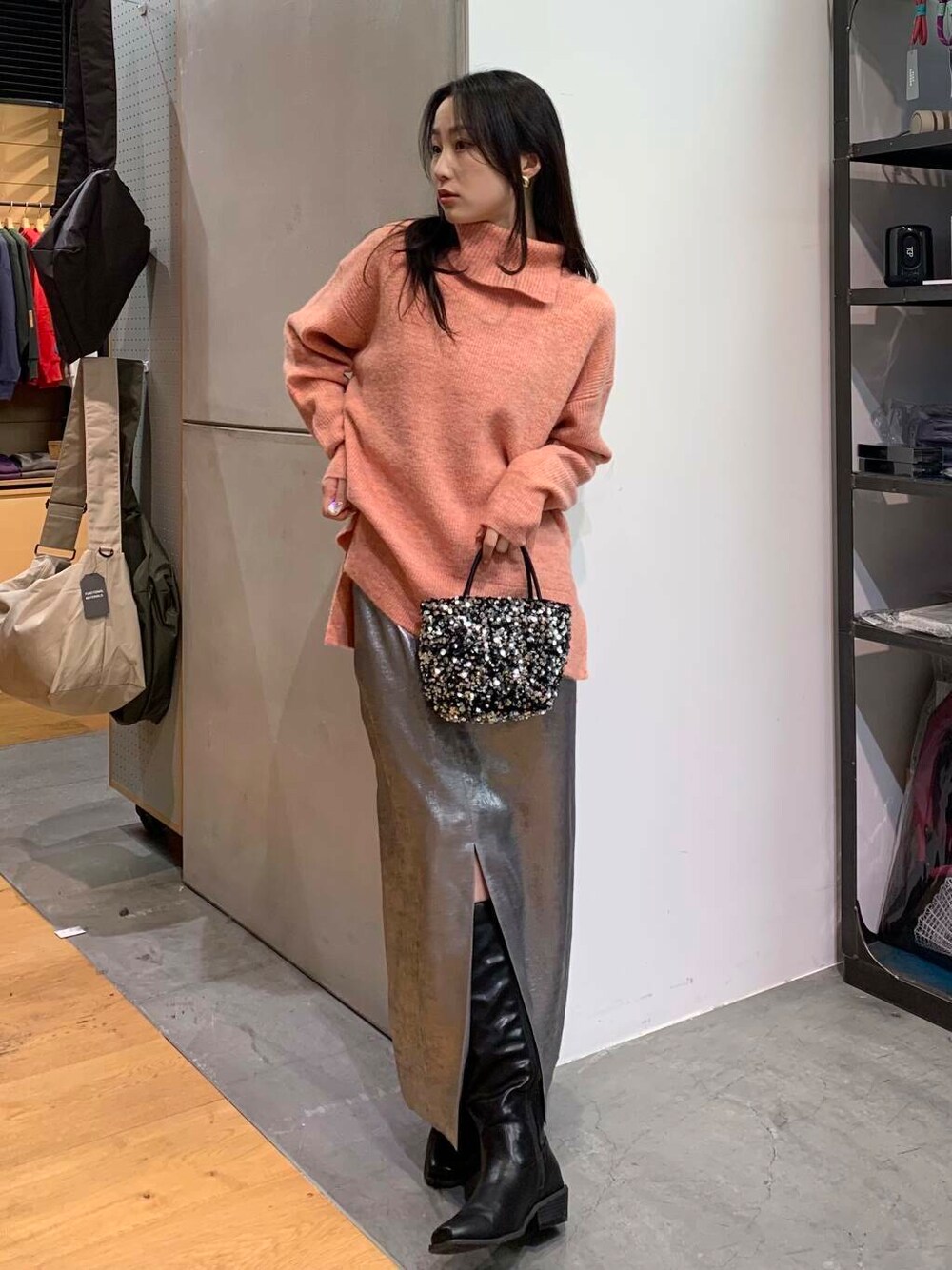 シルバー系のショルダーバッグ、ブラック系のブーツ、シルバー系のスカートを着用したレディースの冬コーディネートの5枚目の写真