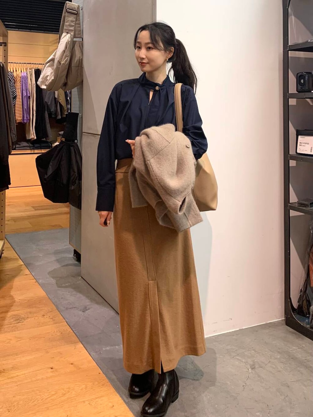 ブラック系のブーツ、ブラウン系のカーディガン/ボレロ、ベージュ系のトートバッグを着用したレディースの秋コーディネートの3枚目の写真