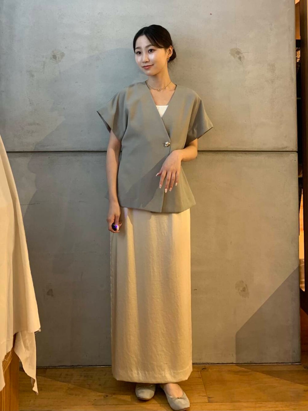 ホワイト系のスカート、ブラウン系のバレエシューズ、グレー系のベストを着用したレディースの秋コーディネートの2枚目の写真