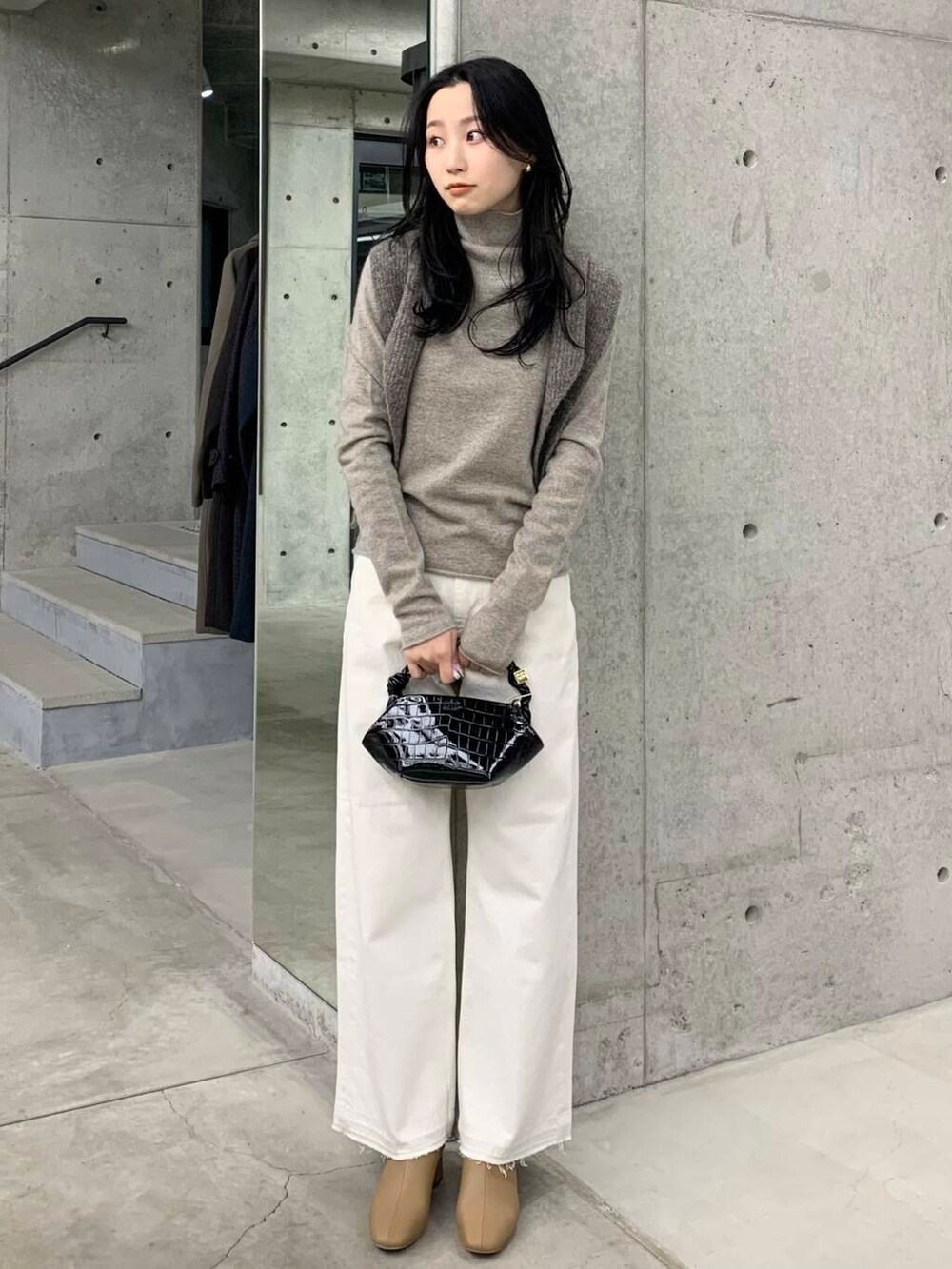 ホワイト系のデニムパンツ、ベージュ系のブーツ、ブラック系のショルダーバッグを着用したレディースの冬コーディネートの3枚目の写真