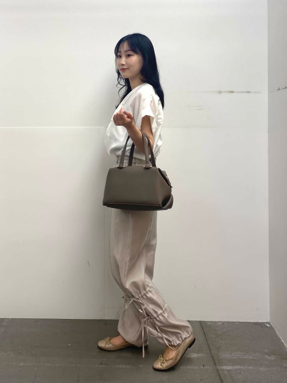 ベージュ系のハンドバッグ、ホワイト系のTシャツ/カットソー、ベージュ系のその他パンツを着用したレディースの夏コーディネートの3枚目の写真
