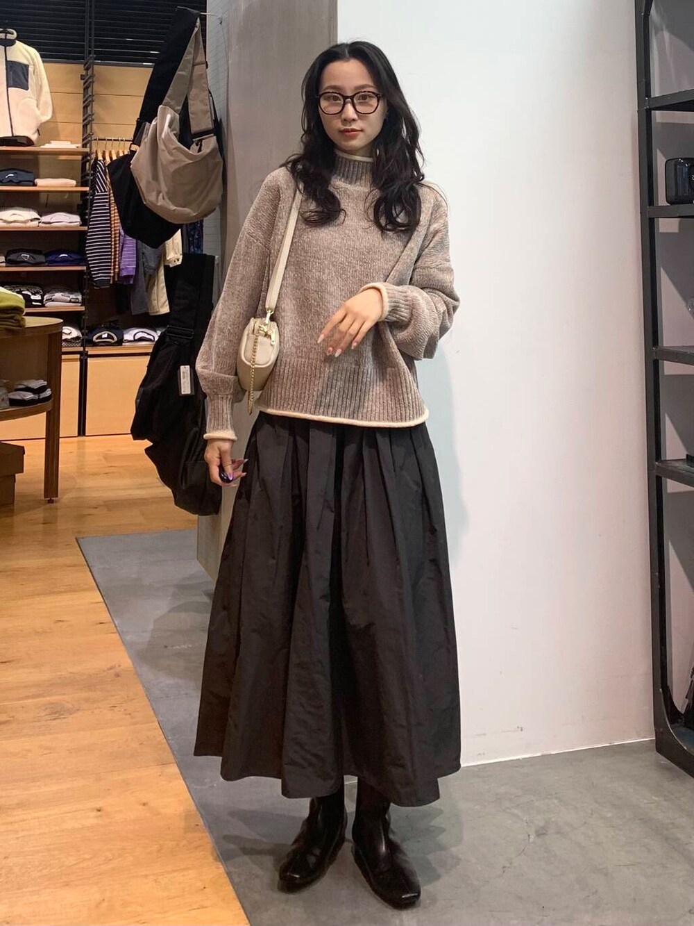 グレー系のスカート、ベージュ系のニット/セーター、ブラック系のブーツを着用したレディースの冬コーディネートの3枚目の写真