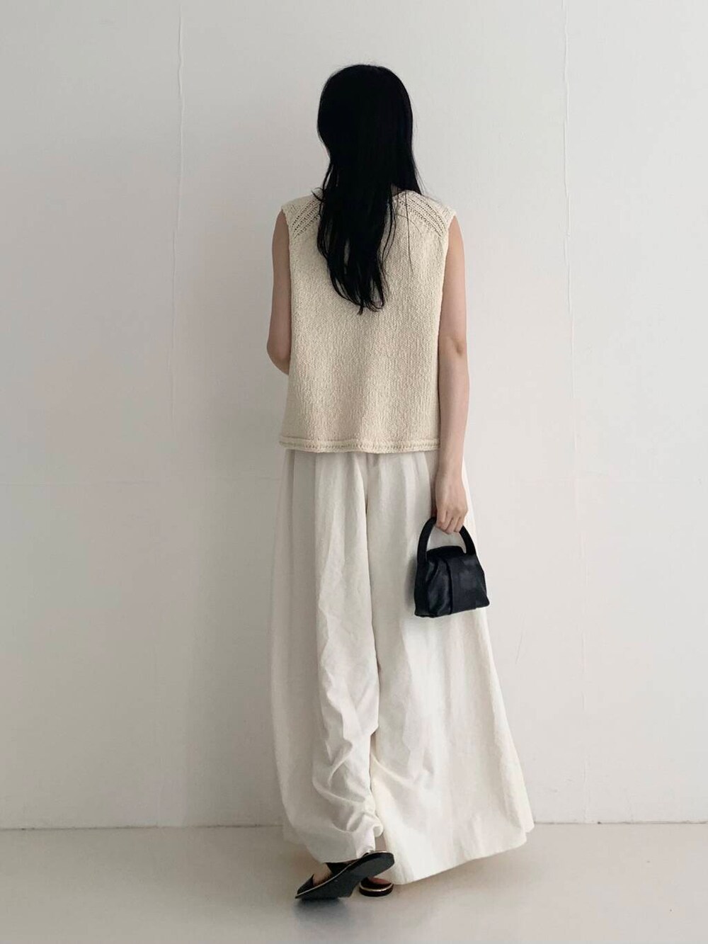 ブラック系のハンドバッグ、ホワイト系のベスト、ホワイト系のその他パンツを着用したレディースの春コーディネートの4枚目の写真