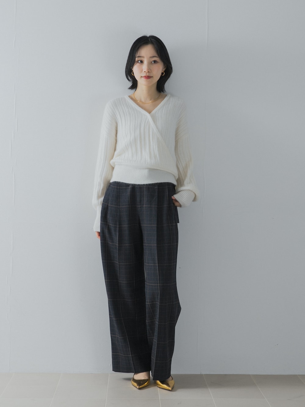 ホワイト系のニット/セーター、ブルー系のその他パンツ、ゴールド系のパンプスを着用したレディースの夏コーディネートの2枚目の写真