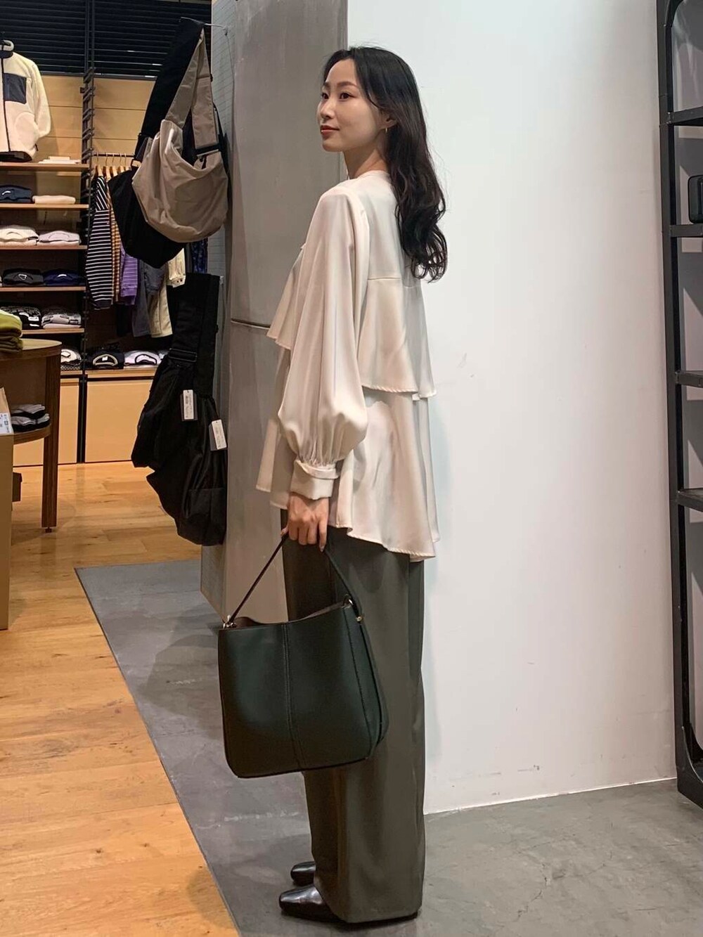 グリーン系のハンドバッグ、ブラック系のブーツ、ホワイト系のシャツ/ブラウスを着用したレディースの冬コーディネートの5枚目の写真