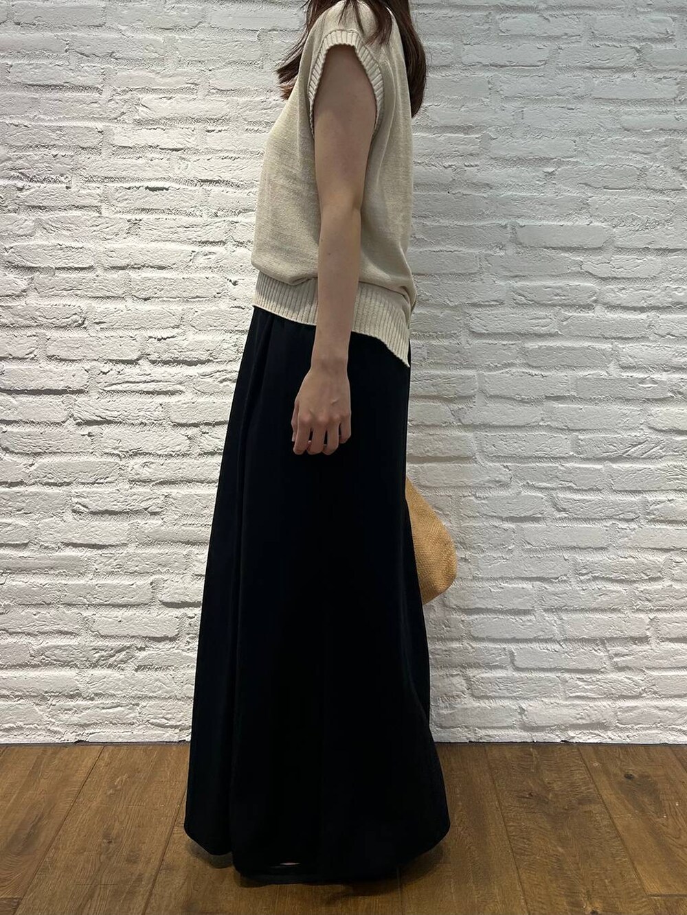 ベージュ系のベスト、ブラック系のスカート、ベージュ系のトートバッグを着用したレディースの夏コーディネートの2枚目の写真