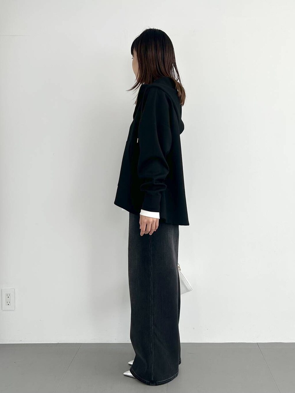 ブラック系のデニムパンツ、ホワイト系のショルダーバッグ、その他のパンプスを着用したレディースの秋コーディネートの2枚目の写真