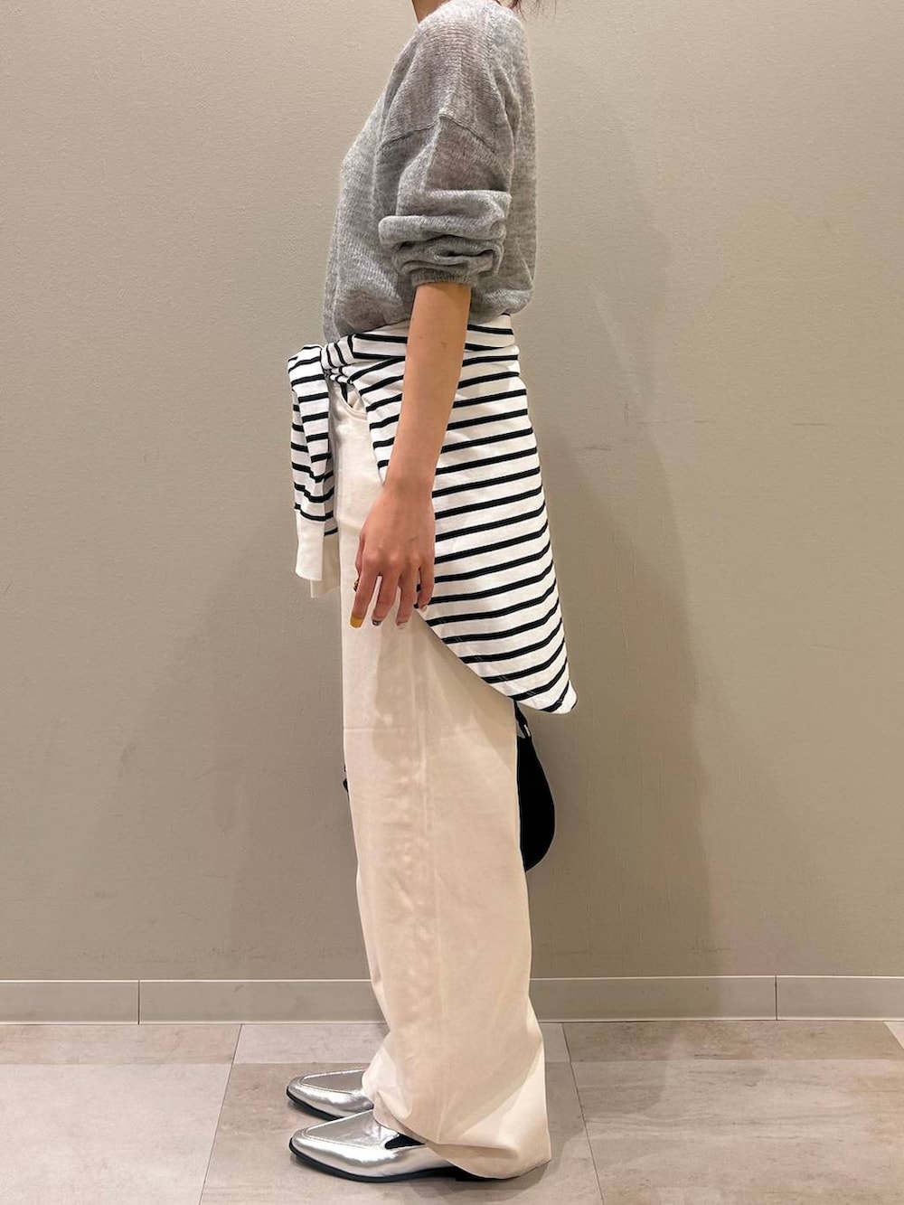 シルバー系のローファー、ブラック系のボディバッグ/ウエストポーチ、グレー系のニット/セーターを着用したレディースの冬コーディネートの2枚目の写真