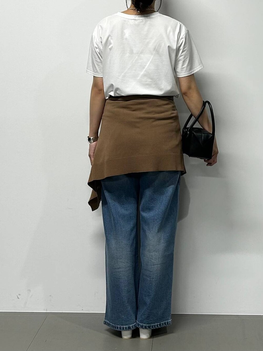 ブルー系のデニムパンツ、ブラック系のハンドバッグ、ホワイト系のTシャツ/カットソーを着用したレディースの夏コーディネートの3枚目の写真