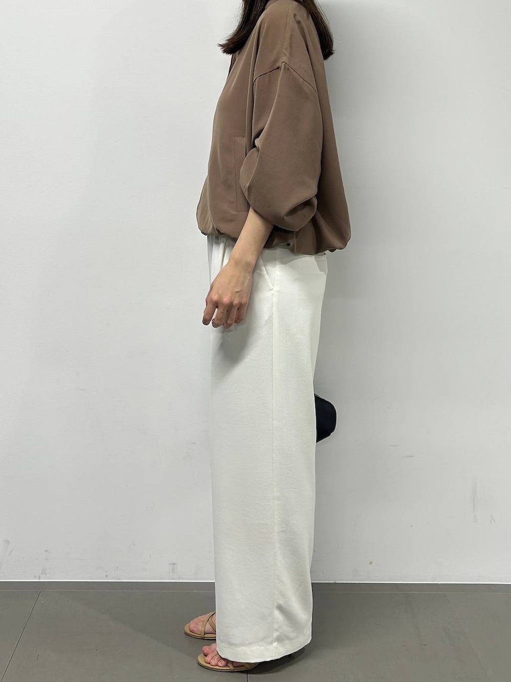 ホワイト系のスラックス、イエロー系のブルゾン、ブラック系のハンドバッグを着用したレディースの春コーディネートの3枚目の写真