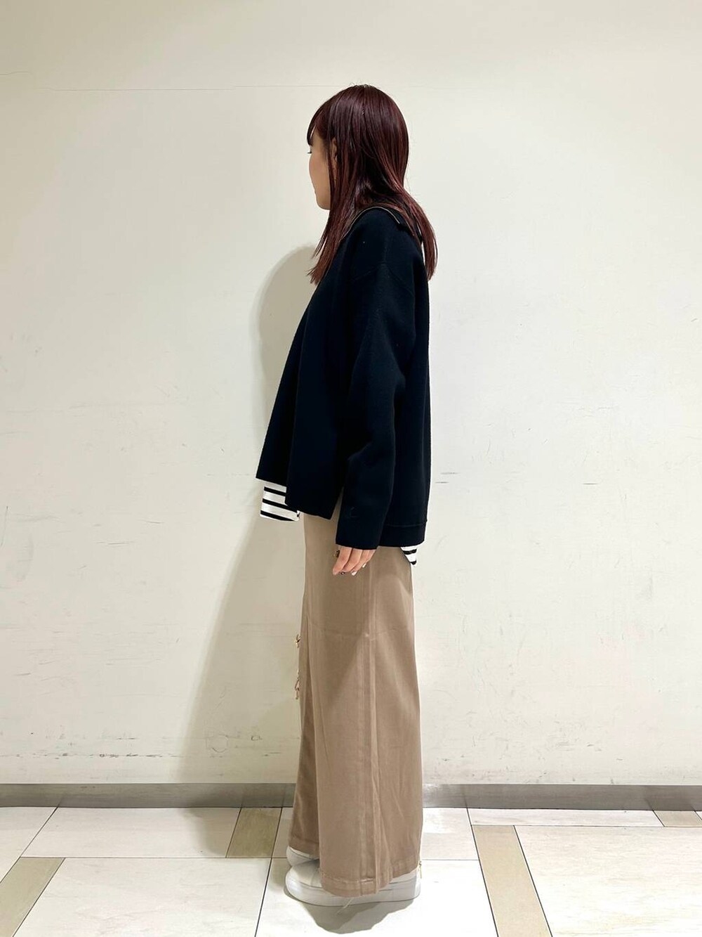 ブラウン系のスカート、ホワイト系のスニーカー、ブラック系のニット/セーターを着用したレディースの冬コーディネートの2枚目の写真