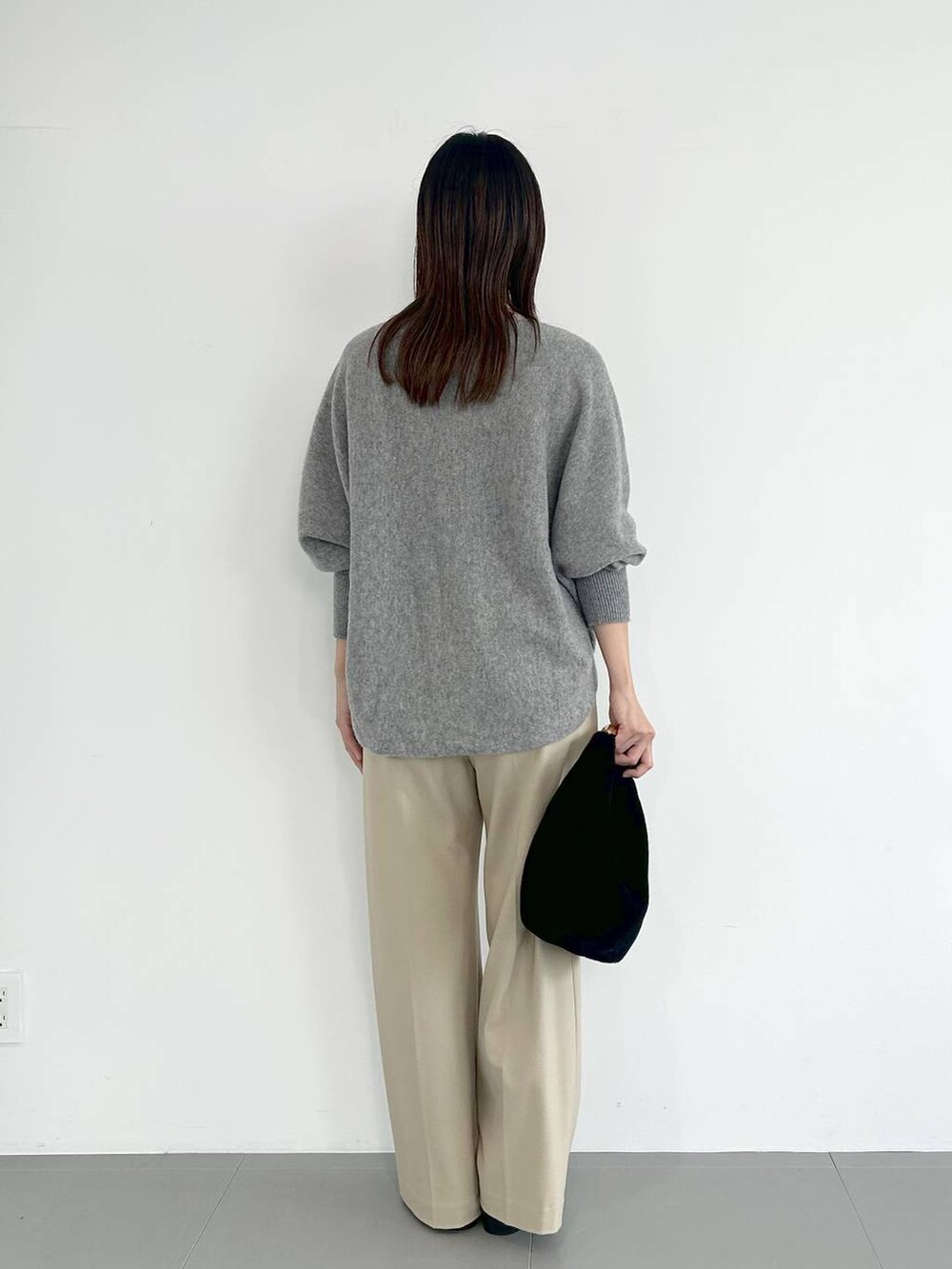 ブラック系のトートバッグ、ブラック系のパンプス、その他のネックレスを着用したレディースの秋コーディネートの3枚目の写真