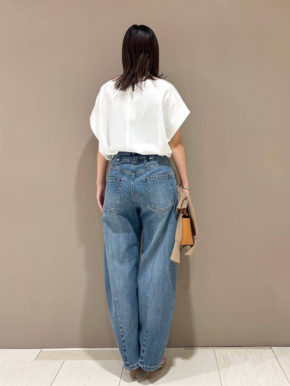 ベージュ系のスリッポン、イエロー系のショルダーバッグ、ブルー系のデニムパンツを着用したレディースの夏コーディネートの5枚目の写真