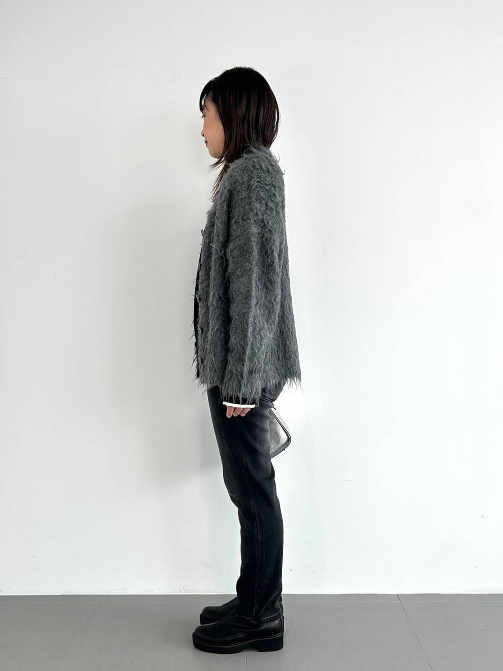 シルバー系のショルダーバッグ、ブラック系のデニムパンツ、ホワイト系のニット/セーターを着用したレディースの秋コーディネートの3枚目の写真