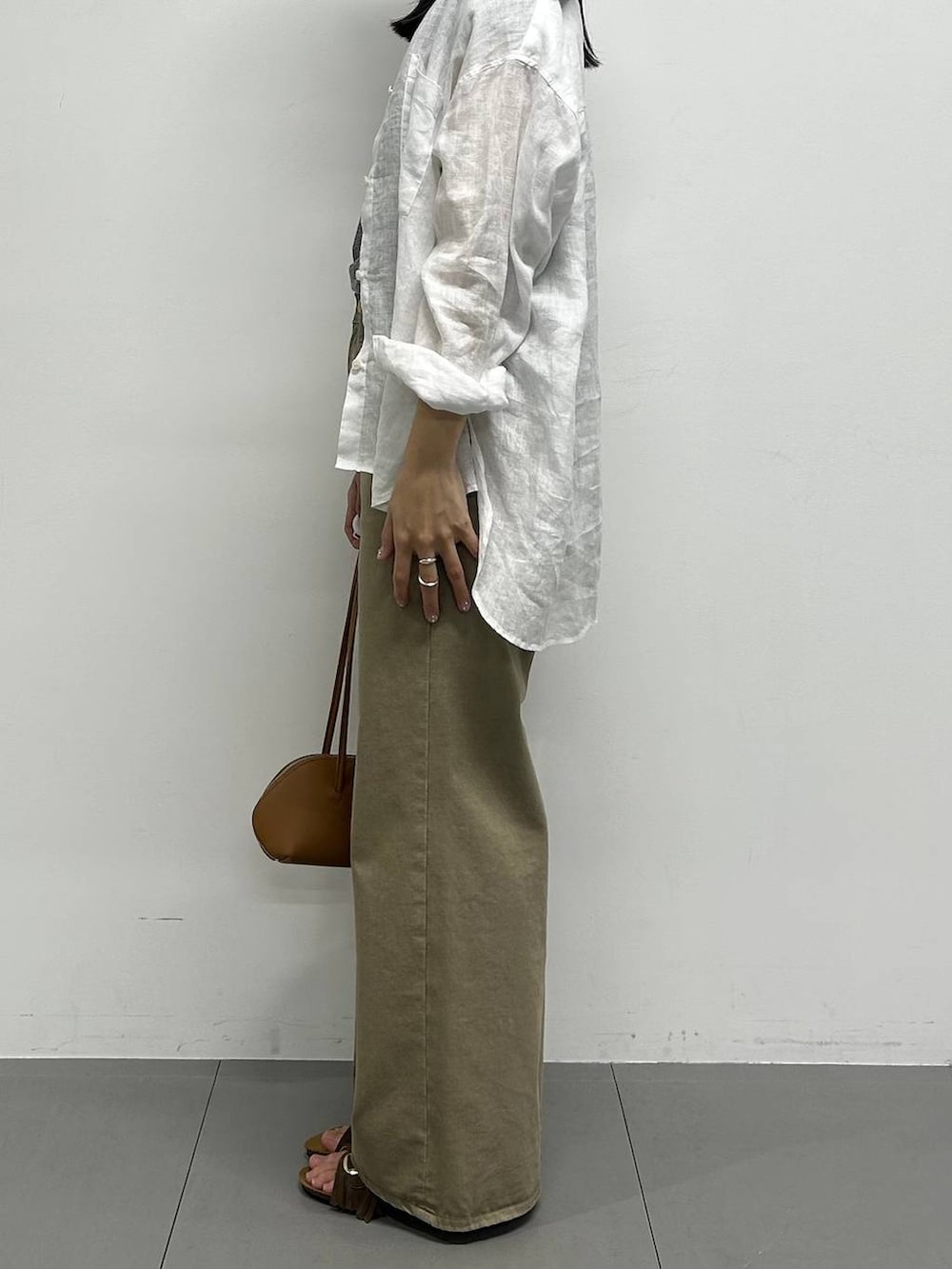 ブラウン系のハンドバッグ、ホワイト系のシャツ/ブラウス、イエロー系のキーホルダーを着用したレディースの春コーディネートの2枚目の写真