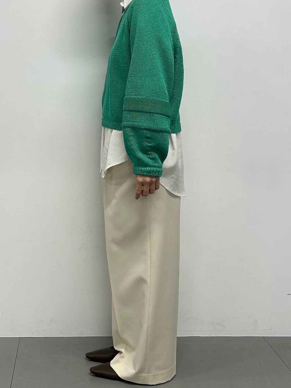 グリーン系のニット/セーター、ホワイト系のシャツ/ブラウス、ブラウン系のパンプスを着用したレディースの冬コーディネートの2枚目の写真