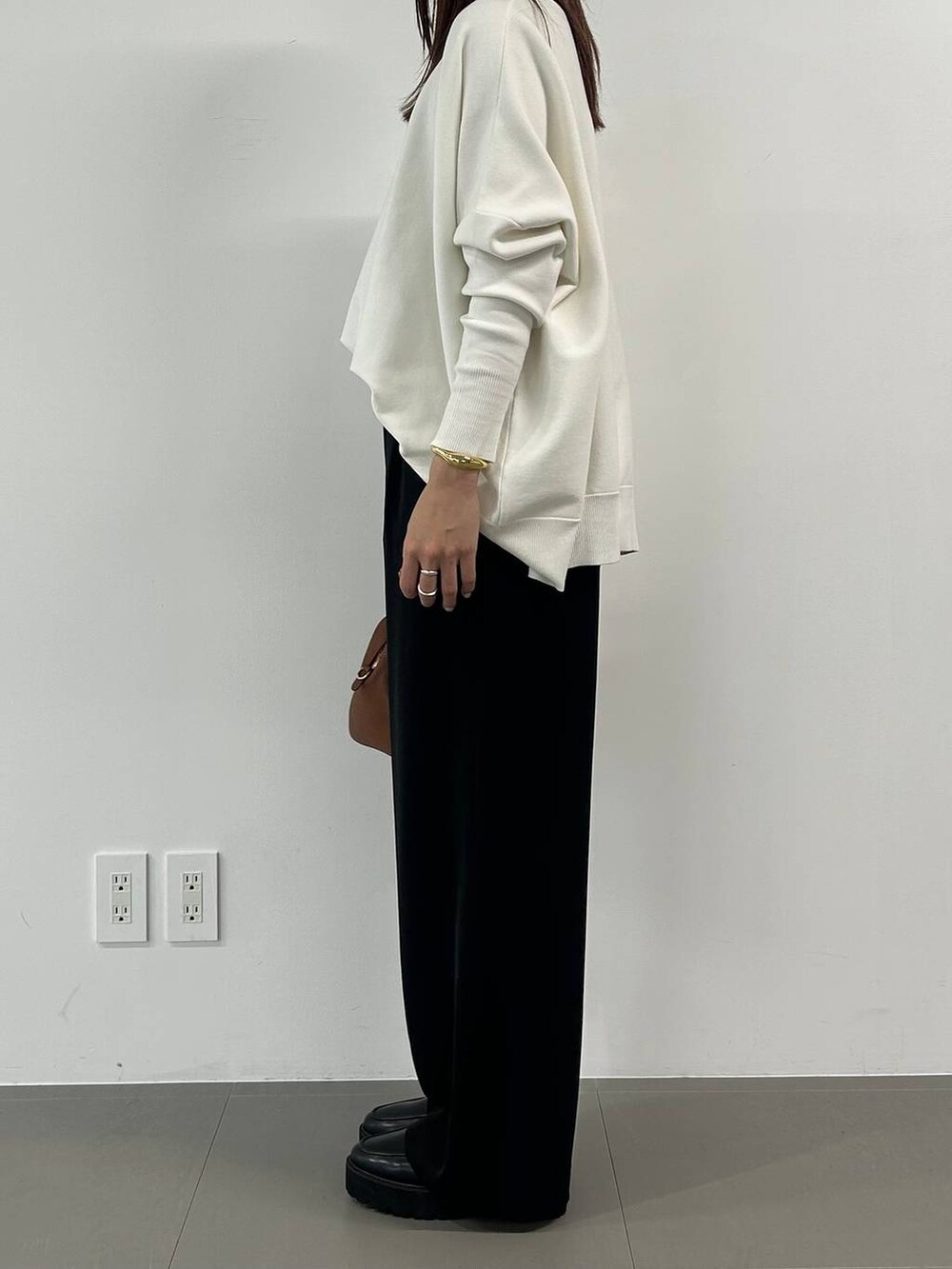 イエロー系のボストンバッグ、ブラック系のスラックス、その他のネックレスを着用したレディースの冬コーディネートの2枚目の写真