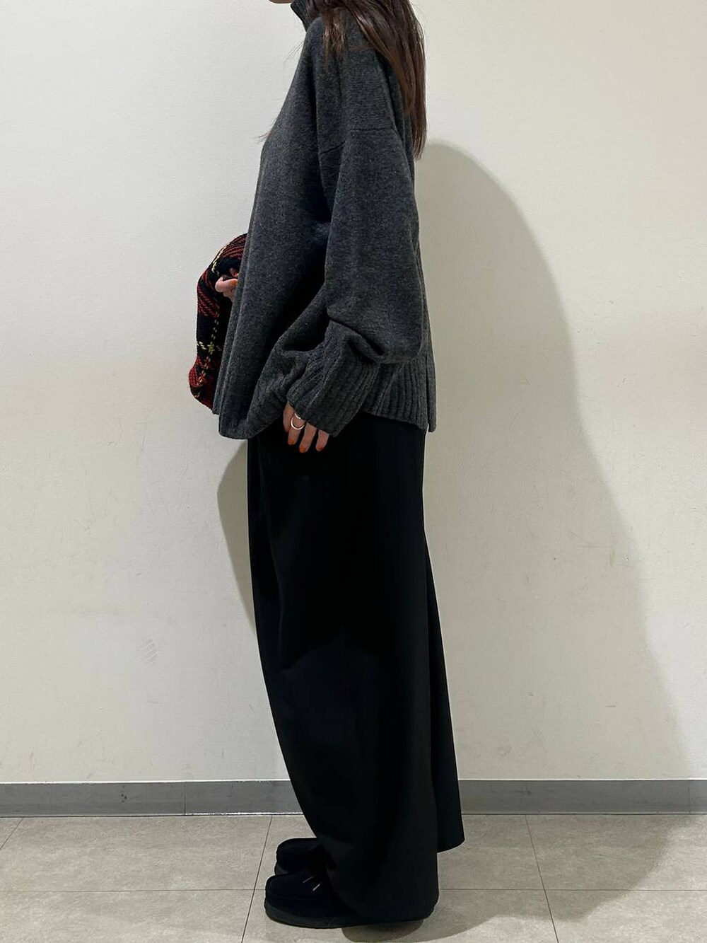 グレー系のニット/セーター、ブラック系のその他パンツ、レッド系のストール/ショールを着用したレディースの冬コーディネートの2枚目の写真