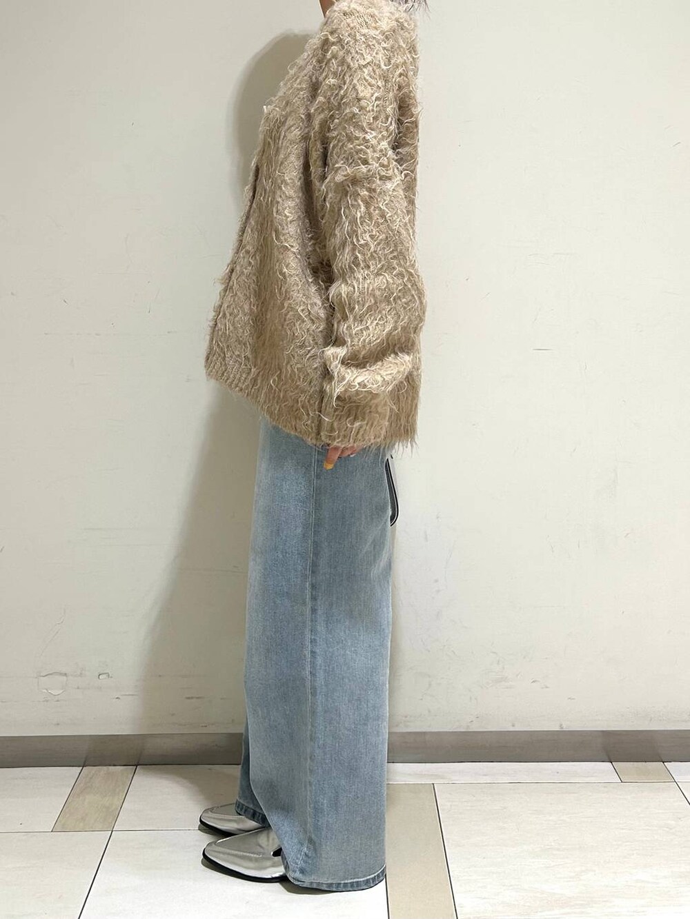 シルバー系のハンドバッグ、シルバー系のローファー、ブルー系のデニムパンツを着用したレディースの冬コーディネートの2枚目の写真
