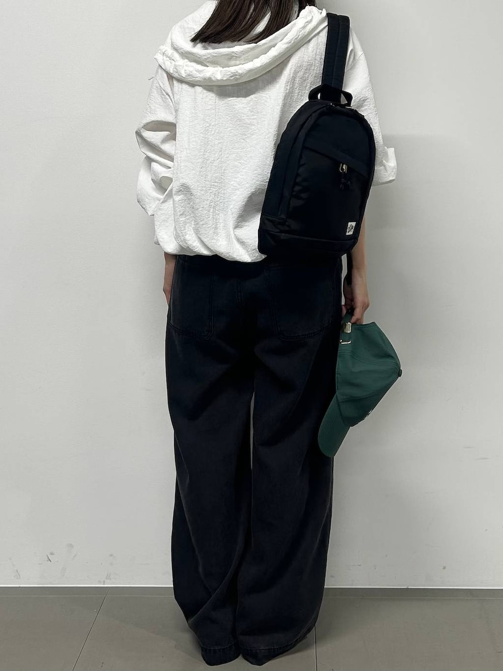 グレー系のデニムパンツ、ホワイト系のブルゾン、ブラック系のサンダルを着用したレディースの春コーディネートの3枚目の写真