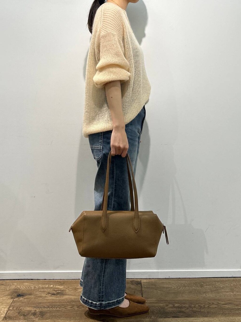 イエロー系のパンプス、ブルー系のデニムパンツ、ベージュ系のニット/セーターを着用したレディースの夏コーディネートの2枚目の写真