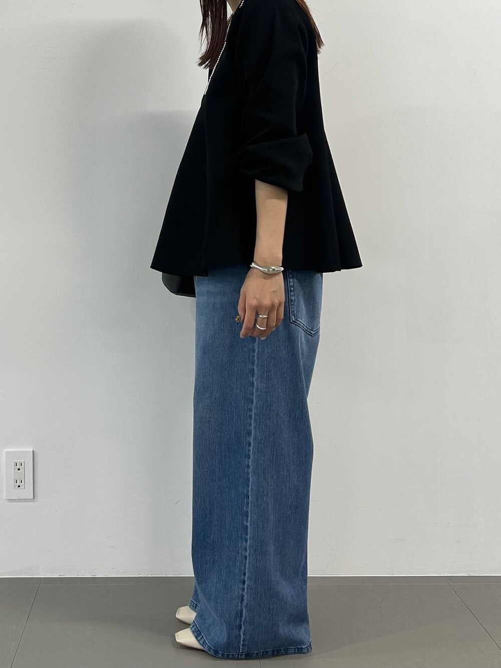 ブルー系のデニムパンツ、ホワイト系のパンプス、ブラック系のニット/セーターを着用したレディースの冬コーディネートの2枚目の写真