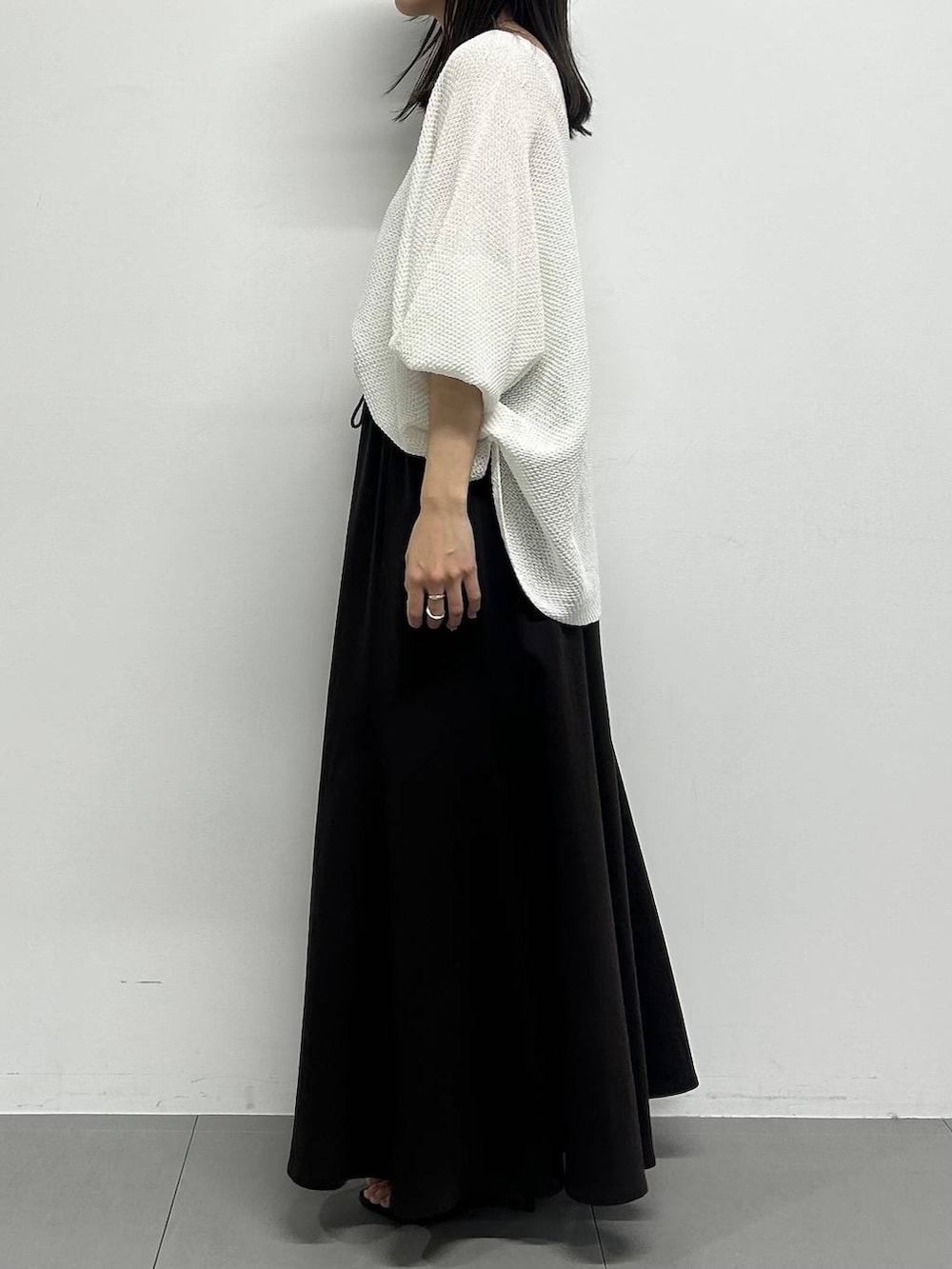 ホワイト系のニット/セーター、ブラック系のサンダル、ベージュ系のかごバッグを着用したレディースの春コーディネートの2枚目の写真