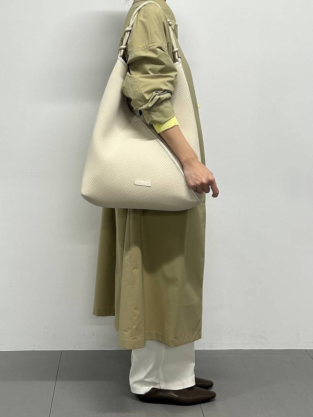 イエロー系のニット/セーター、ホワイト系のカーゴパンツ、ブラウン系のパンプスを着用したレディースの冬コーディネートの2枚目の写真