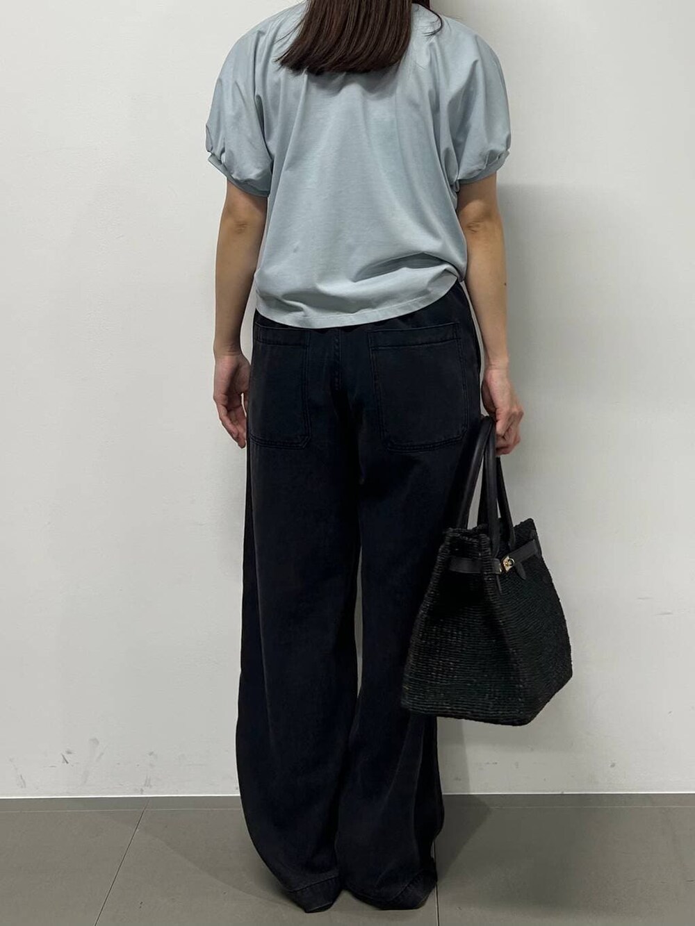 グレー系のデニムパンツ、ブラック系のかごバッグ、ブラック系のサンダルを着用したレディースの春コーディネートの2枚目の写真