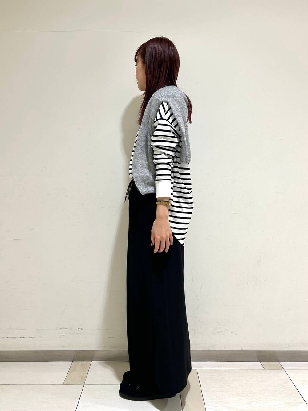 ブラック系のスカート、グレー系のニット/セーター、ホワイト系のTシャツ/カットソーを着用したレディースの冬コーディネートの2枚目の写真