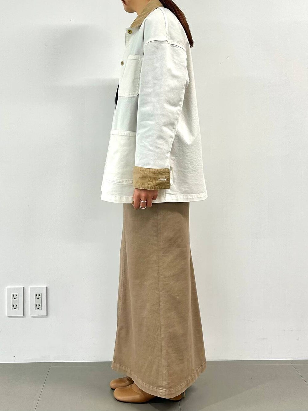 ブラウン系のスカート、ベージュ系のブーツ、ブラウン系のハンドバッグを着用したレディースの冬コーディネートの2枚目の写真