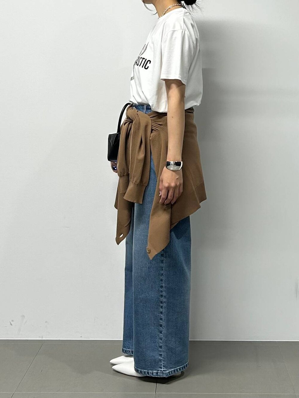 ブルー系のデニムパンツ、ブラック系のハンドバッグ、ホワイト系のTシャツ/カットソーを着用したレディースの夏コーディネートの2枚目の写真