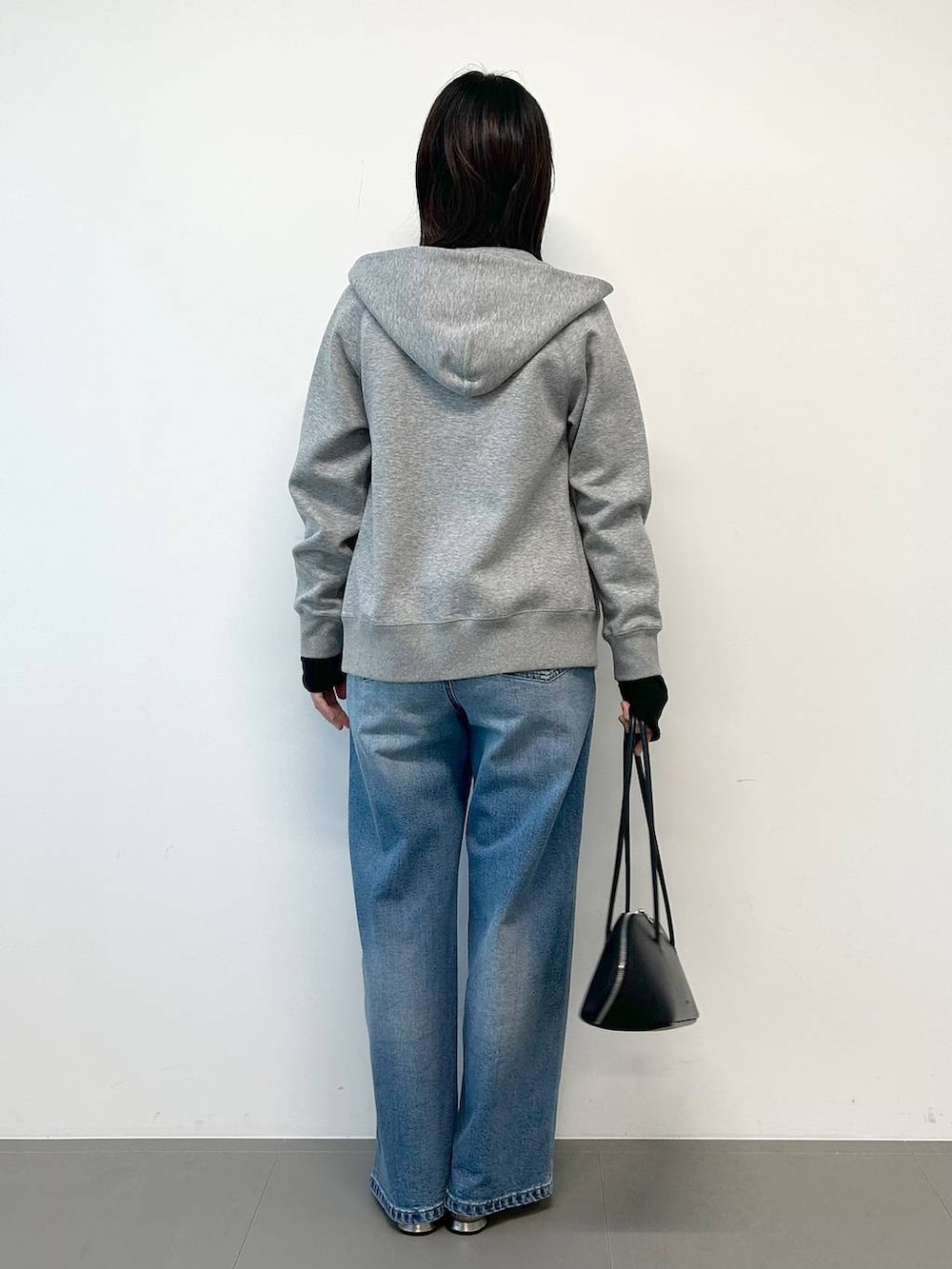 ブルー系のデニムパンツ、ブラック系のトートバッグ、シルバー系のパンプスを着用したレディースの秋コーディネートの3枚目の写真